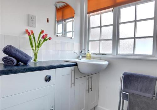 een witte badkamer met een wastafel en een spiegel bij Stable Mews Cottage in Royal Tunbridge Wells