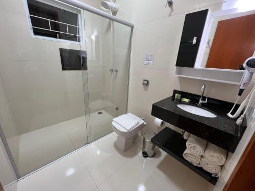 a bathroom with a shower toilet and a sink at Pousada Terra Rossa in São José do Rio Pardo