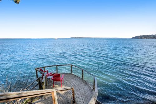 two red chairs sitting on a dock in the water at Olympus View Home in Port Ludlow