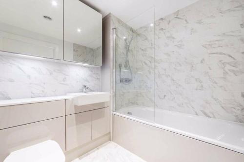 Baño blanco con bañera y lavamanos en Modern & Spacious Luxury Flat-10 min to London Eye, en Londres