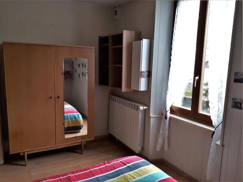 Cette chambre comprend une armoire, un lit et une fenêtre. dans l'établissement Appartement La Roche sur Foron, à La Roche-sur-Foron
