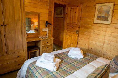 a bedroom with a bed with towels on it at Stable Lodge in Drymen