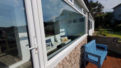 a window with a blue chair on a balcony at A View With A Room in Penrhyn Bay