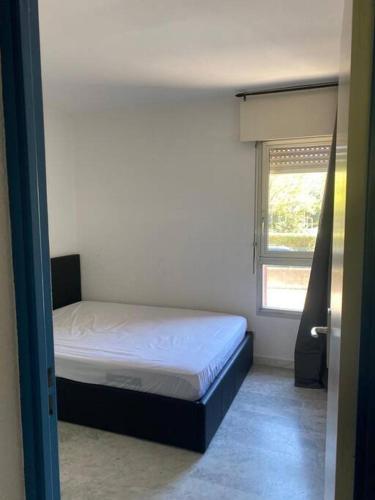 une petite chambre avec un lit et une fenêtre dans l'établissement Appartement le petit port, au Cap d'Agde