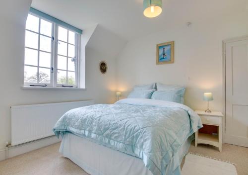 a white bedroom with a bed and a window at The Coach House in Biddenden