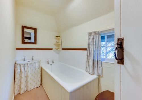 ein Bad mit einer Badewanne, einem Waschbecken und einem Fenster in der Unterkunft Thatch Cottage in Shoreham-by-Sea