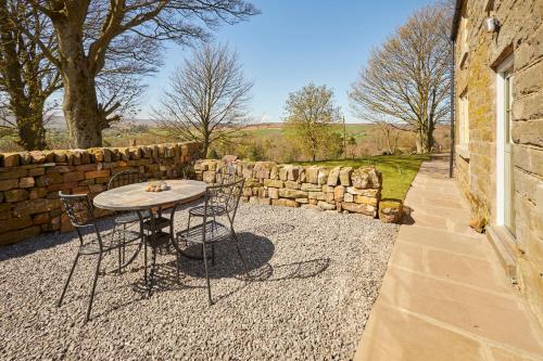 a table and chairs in front of a stone wall at Host & Stay - Lop Hall in Danby