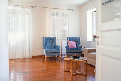 a living room with two blue chairs and a table at Naias Aegina, Sea-front apartment 95 sqm in Aegina Town