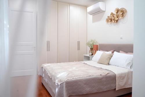 um quarto branco com uma cama com armários brancos em Naias Aegina, Sea-front apartment 95 sqm em Egina