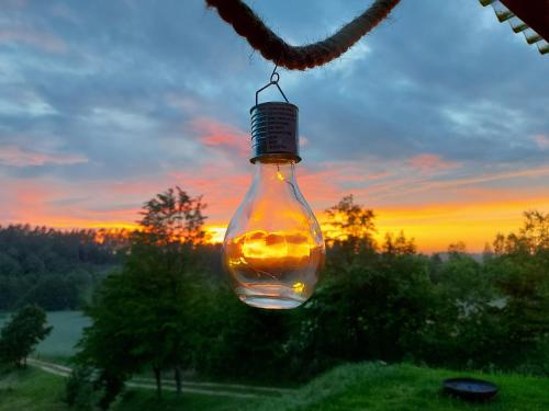 a light bulb hanging from a chain with a sunset in the background at Sielski Domek Na Wzgórzu in Sulęczyno