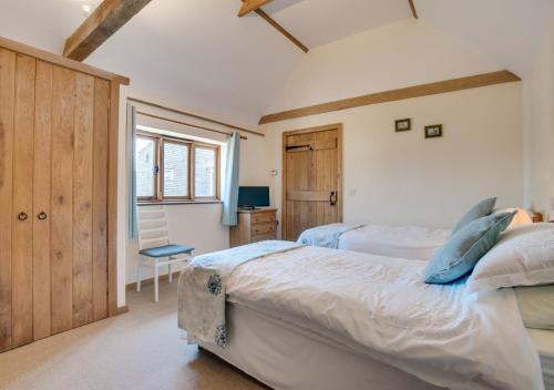 a bedroom with two beds and a desk and a window at The Cowshed in Herstmonceux