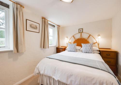 a bedroom with a large bed and two windows at The Little House in Rolvenden