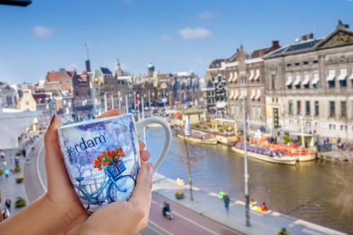 a person holding up a cup in front of a river at Hotel des Arts in Amsterdam