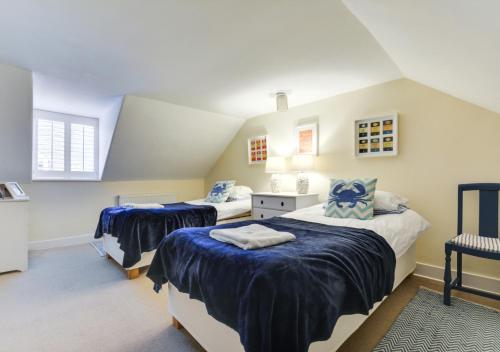 a attic bedroom with two beds and a chair at The Old Sweet Shop in Whitstable