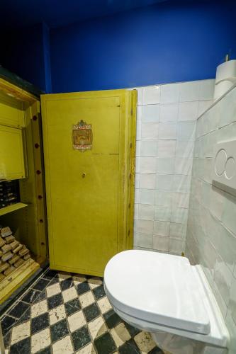 a bathroom with a toilet and a yellow door at Hotel des Arts in Amsterdam