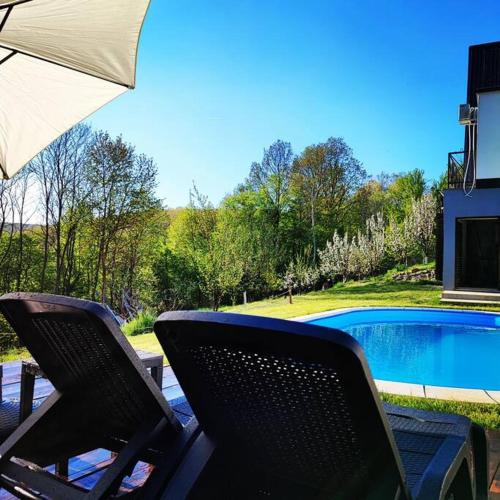 two chairs and an umbrella next to a swimming pool at Linden Forest House in LipoviC(244)ka Mehana