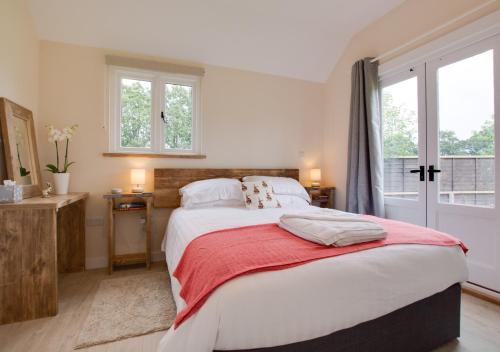 a bedroom with a large bed with a red blanket at The Warren in Biddenden