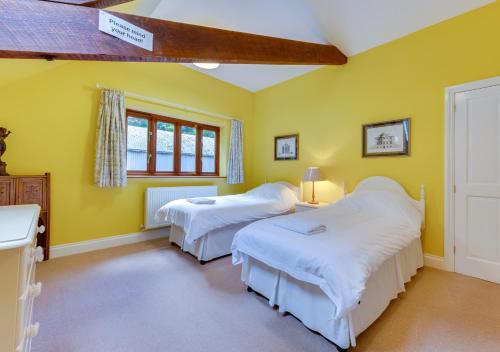 2 camas en una habitación con paredes amarillas en Valley View Barn en Hartfield