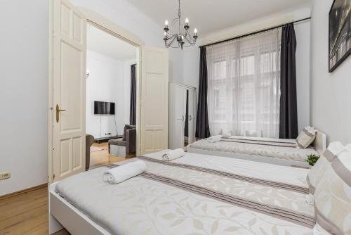 a white bedroom with two beds and a window at Real Apartments Wesselényi in Budapest