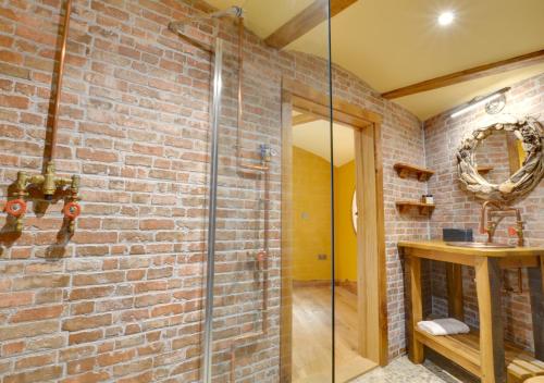 a bathroom with a brick wall and a glass shower at Vineyard Hollow in Bodiam