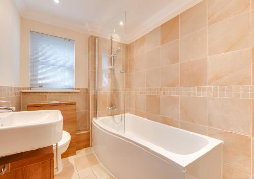 a bathroom with a white tub and a sink at York Mansions Apartment in Broadstairs
