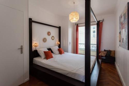 une chambre avec un lit avec des draps blancs et des oreillers orange dans l'établissement L39 Suite Promenade des Anglais, Vue Mer/Terrasse&WIFI, à Nice