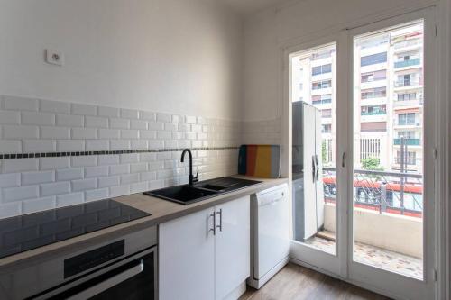 La cuisine blanche est équipée d'un évier et d'un réfrigérateur. dans l'établissement L39 Suite Promenade des Anglais, Vue Mer/Terrasse&WIFI, à Nice