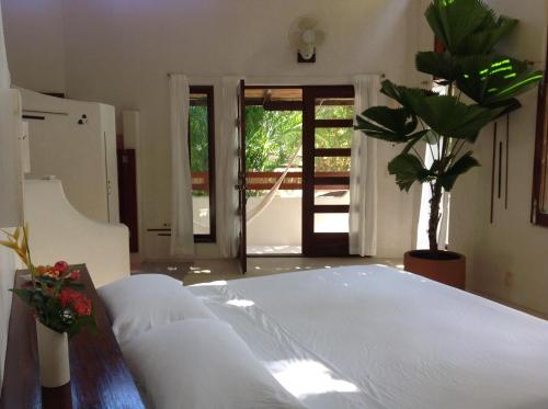 a bedroom with a white bed and a plant at Casa Flor de Mar in Zipolite