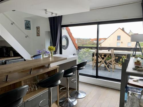 a kitchen with a counter and chairs and a large window at DUPLEX AVEC JACUZZI vue imprenable sur la baie de Wissant in Wissant