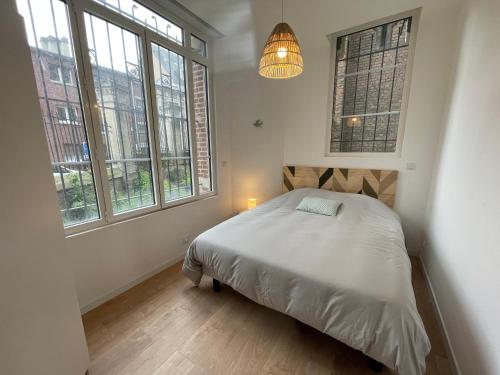 1 dormitorio con 1 cama en una habitación con ventanas en L'Oratoire en Amiens