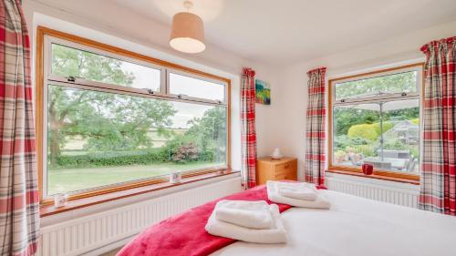 a bedroom with a bed and two windows at Ellencroft in Unstone