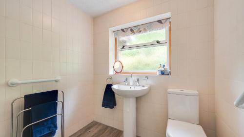 a bathroom with a sink and a toilet and a window at Ellencroft in Unstone