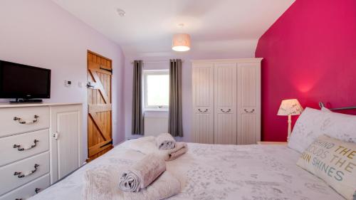 een slaapkamer met een wit bed en een roze muur bij Farriers Cottage in Ilam