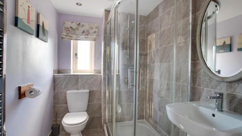 een badkamer met een douche, een toilet en een wastafel bij Farriers Cottage in Ilam