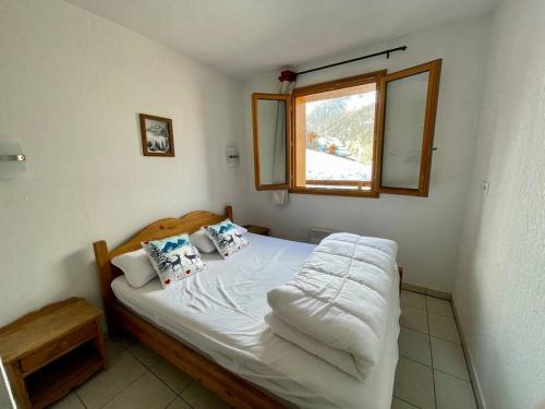 1 dormitorio con 1 cama blanca y ventana en Appartement Les Orres 1800 - Vue montagne en Les Orres