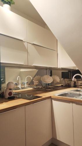 une cuisine avec des armoires blanches et un comptoir dans l'établissement Cozy Studio Paris 16ème - Arc de Triomphe, Champs Elysées & Trocadero, à Paris