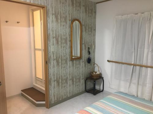 een slaapkamer met een bed, een spiegel en een raam bij Accommodation Service B&B in Miyazaki
