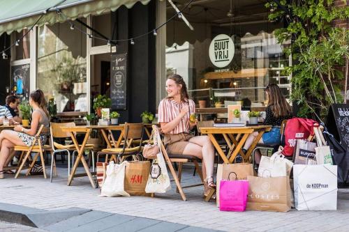 a group of women sitting at tables outside a store with shopping bags at Gezellig appartement, Gerenoveerd eind 2022 in Tilburg