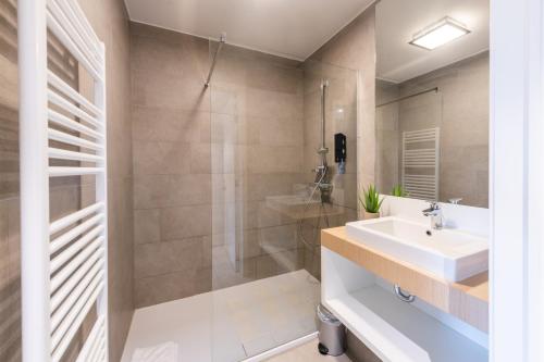een badkamer met een wastafel en een douche bij Belcasa Family Suites & Lofts in Middelkerke