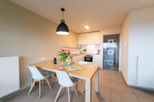 a kitchen and dining room with a table and chairs at Belcasa Family Suites & Lofts in Westende