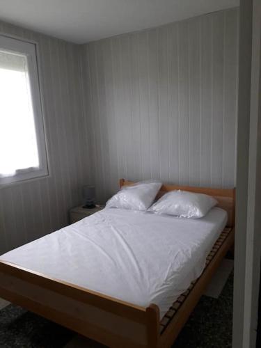 une chambre avec un lit avec des draps blancs et des oreillers dans l'établissement Gite Au Marianne, à Jû-Belloc