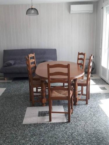 einen Tisch und Stühle in einem Zimmer mit Sofa in der Unterkunft Gite Au Marianne in Jû-Belloc