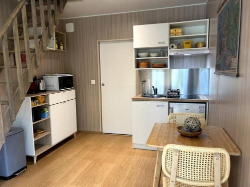 une cuisine avec une table et des chaises dans une pièce dans l'établissement Ma cabane sous les arbres, à Soulac-sur-Mer