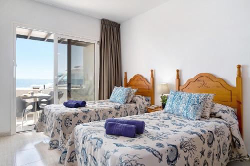 two beds in a bedroom with a view of the ocean at Callao Beach 3 in Arrieta