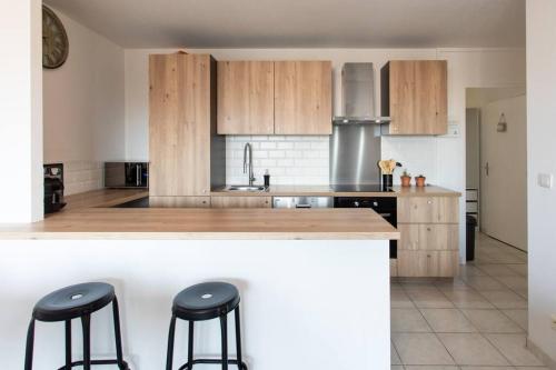 une cuisine avec des armoires en bois et un comptoir avec des tabourets dans l'établissement L41 Suite Paladium 8pax 4rooms balcony WIFI AC, à Nice