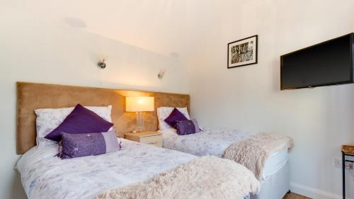 a bedroom with two beds with purple pillows at Field Barn in Matlock