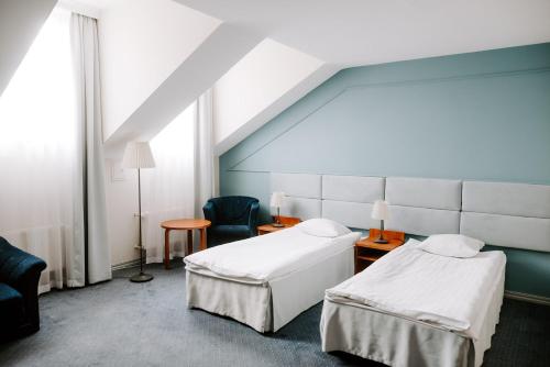 a hospital room with two beds and a chair at Hotel Senator in Zamość