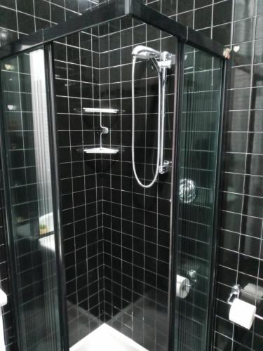 a black tiled shower with a glass door at Casa Guen Parma in Parma