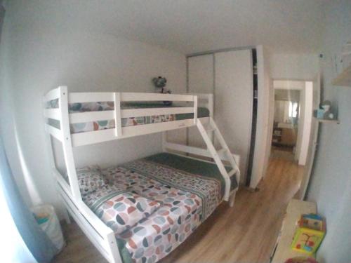 ein weißes Etagenbett in einem Zimmer mit einem Schlafzimmer in der Unterkunft L'Octan Océan in Saint-Leu