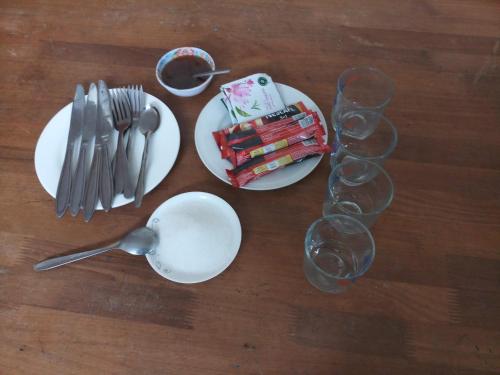 een tafel met borden en wijnglazen en een lepel bij You hour homestay in Sa Pa